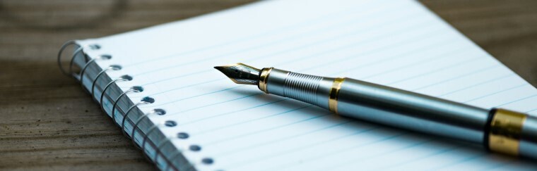 Un stylo plume et un carnet de notes sur un bureau