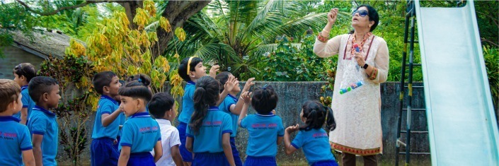 Group of Sri Lankan children outside with adult blowing bubbles