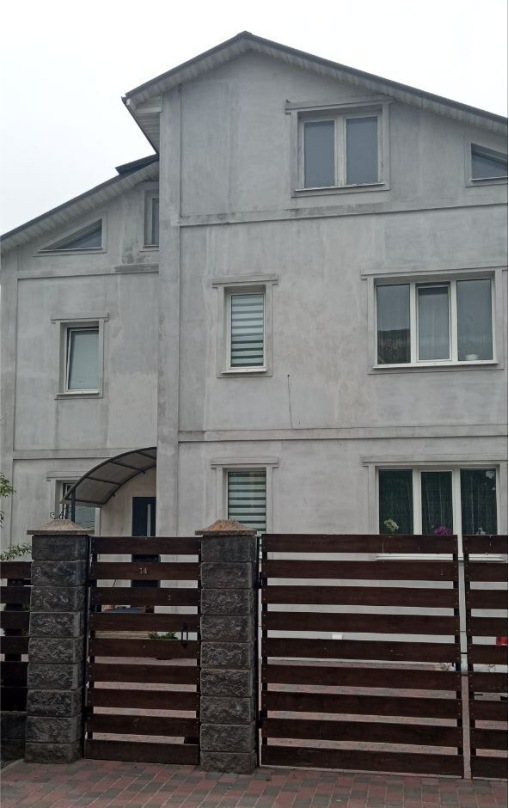 Whitegrey cement church building with brown wooden fence surrounding facility