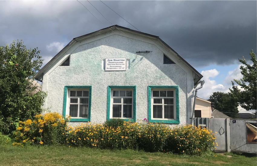 Smaller single-story church building with green lawn and shrubs