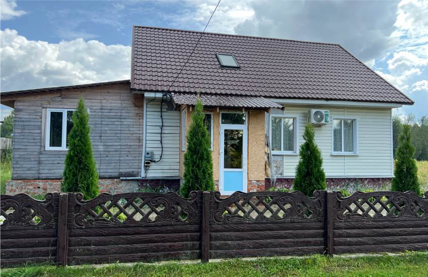 A church building looking much like a house with brown lattice fence and shrubs