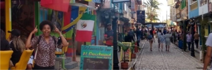 Smiling young woman standing under a Canadian flag in on Colombian street.